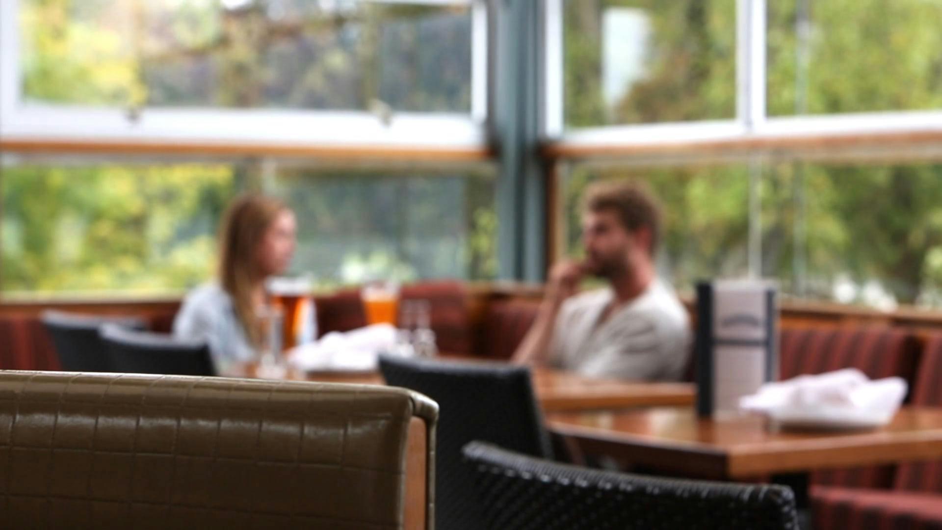A Couple Enjoying A Drink And Talking Inside A Cozy Cafe.